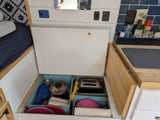 RV rental's compact kitchen with organized under-bed storage revealing bins of cooking essentials and a toaster.