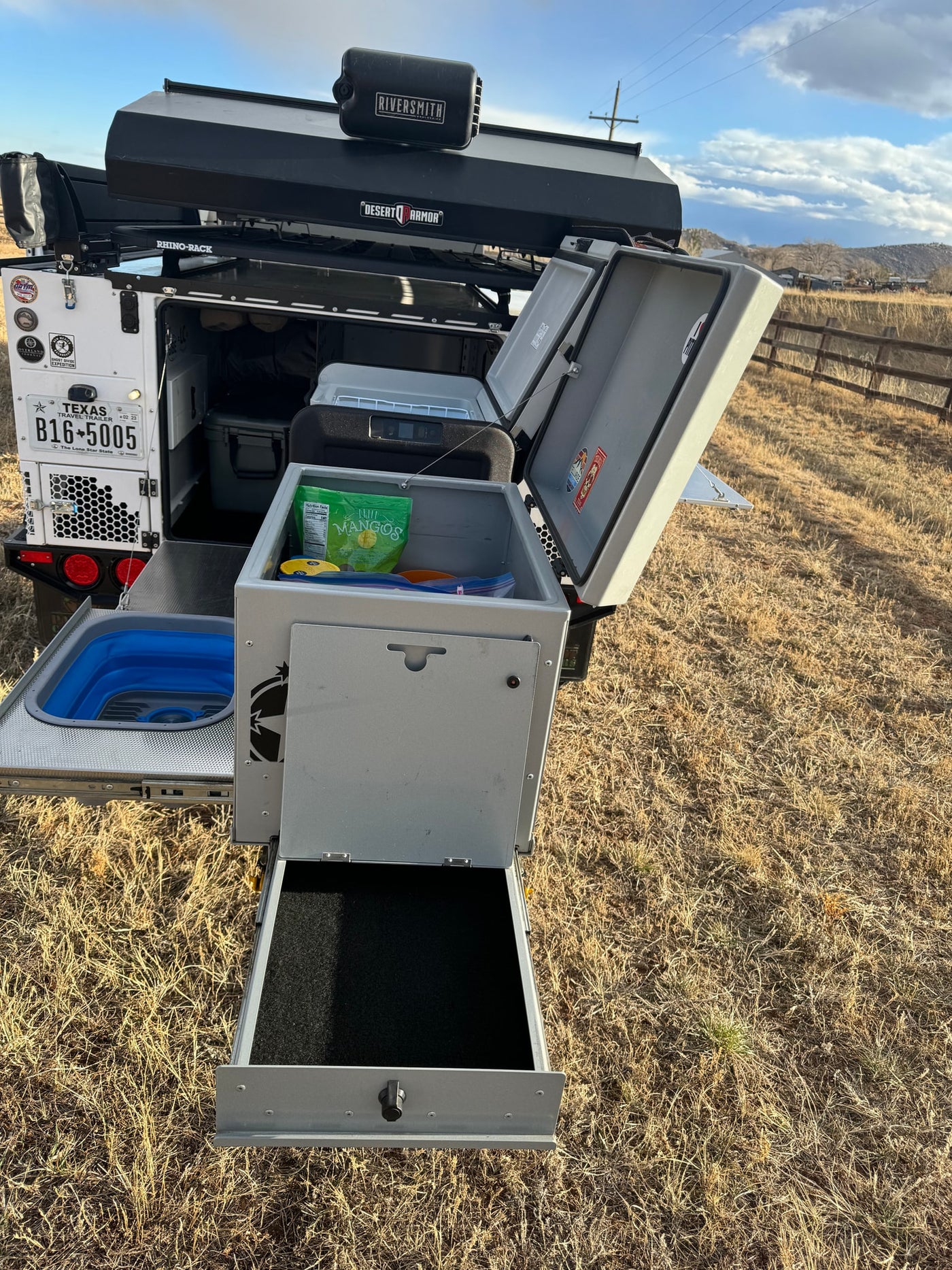 This RV rental features an open overland travel trailer, showcasing its integrated outdoor kitchen, fridge, and pull-out storage solutions. — photo 10