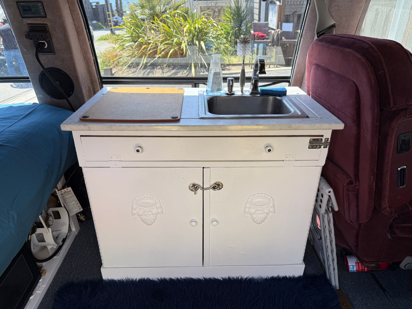 Experience your RV rental's compact kitchen: sink, cutting board, and cozy interior comforts for your journey.