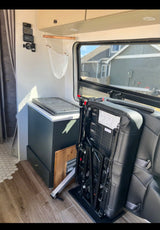 RV rental's versatile interior: features a fold-down seat, fridge, monitors, and compact living space.