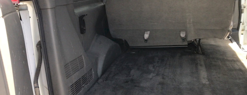 RV rental interior: Rear cargo area with a dark carpeted floor, a bench seat with buckles, and side wall paneling. — photo 4