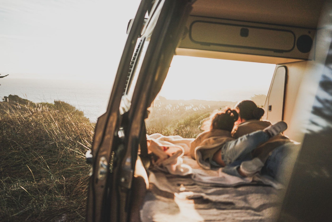  with two people relaxing inside.|Two kids cozy up inside an RV rental camper van with its pop-top open — photo 3