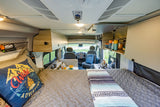 An RV rental's clever interior. From the comfy bed, see the compact kitchen, storage, and front cabin ready for travel.