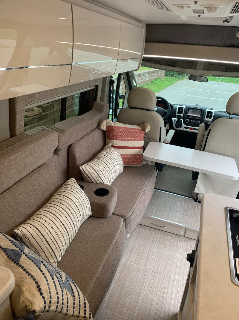Inside a sleek rv rental: a comfy living space with throw pillows, glossy cabinets, and front cockpit area. — photo 12