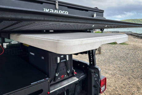 This RV rental setup features a rooftop tent, pull-out table, fridge, and kitchen system for vehicle camping.