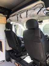 RV rental interior with black front seats, one swiveled, and overhead rolled storage, ideal for van life adventures.