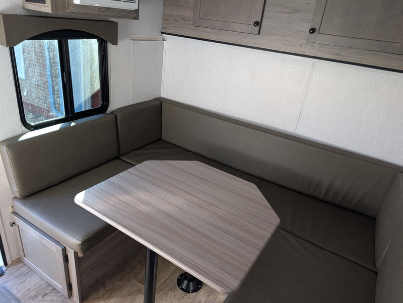 RV rental dinette featuring comfortable U-shaped seating, a wood-grain table, and a sunlit window. — photo 17