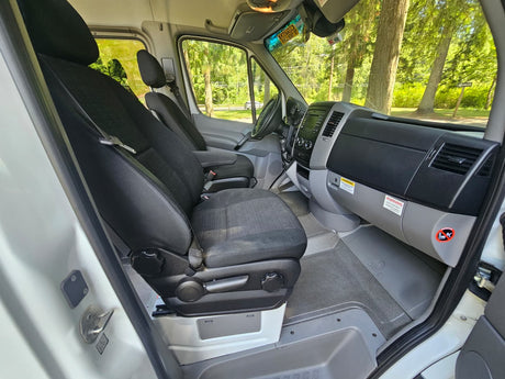 RV rental van's front cabin: black driver & passenger seats, detailed dashboard. Key visible on seatbelt.