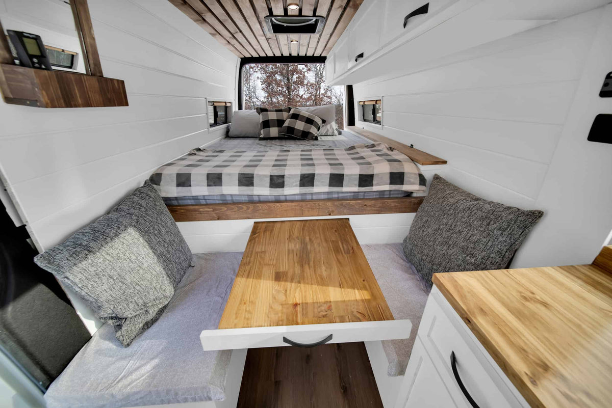 Cozy camper van interior with a bed, dining area, and wood accents, perfect for an RV rental adventure. — photo 8