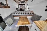 Cozy camper van interior with a bed, dining area, and wood accents, perfect for an RV rental adventure.