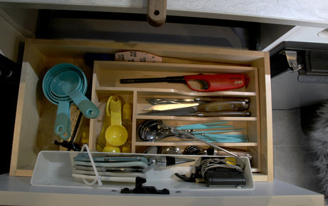 Neatly organized kitchen drawer in an RV rental, packed with measuring cups, knives, & essential cooking utensils for your trip.