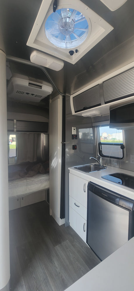 Modern RV rental interior with full kitchen, bedroom, and essential amenities for comfortable travel.