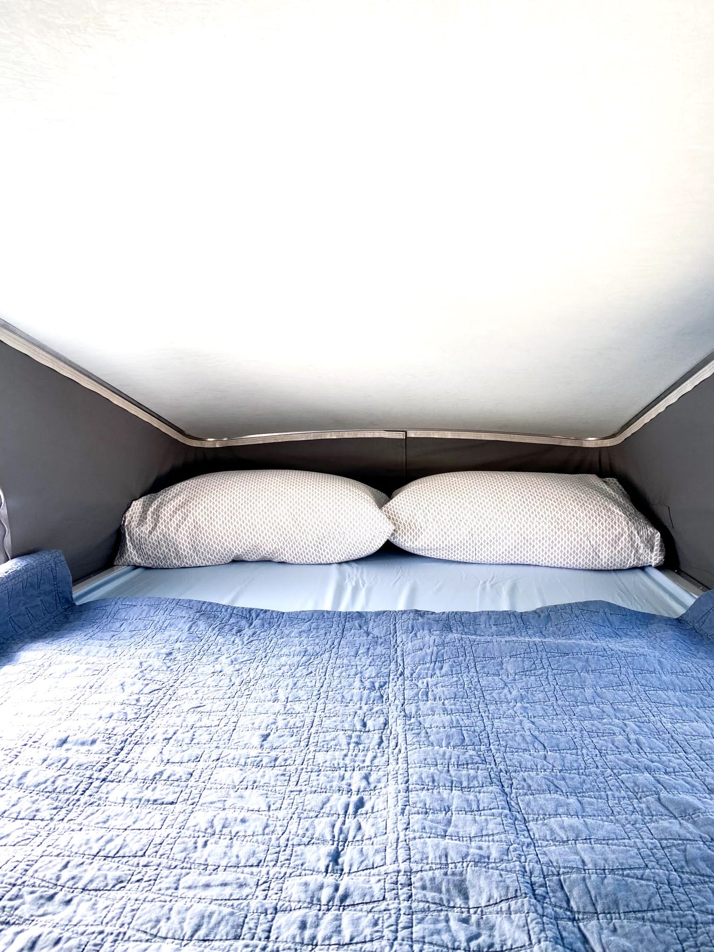 Cozy, raised sleeping area in an RV rental, featuring a comfortable bed with blue bedding and patterned pillows. — photo 9