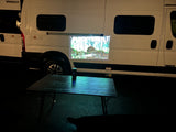 Outdoor cinema with an RV rental! A projector casts a nature scene onto a white Winnebago Solis camper van at night.