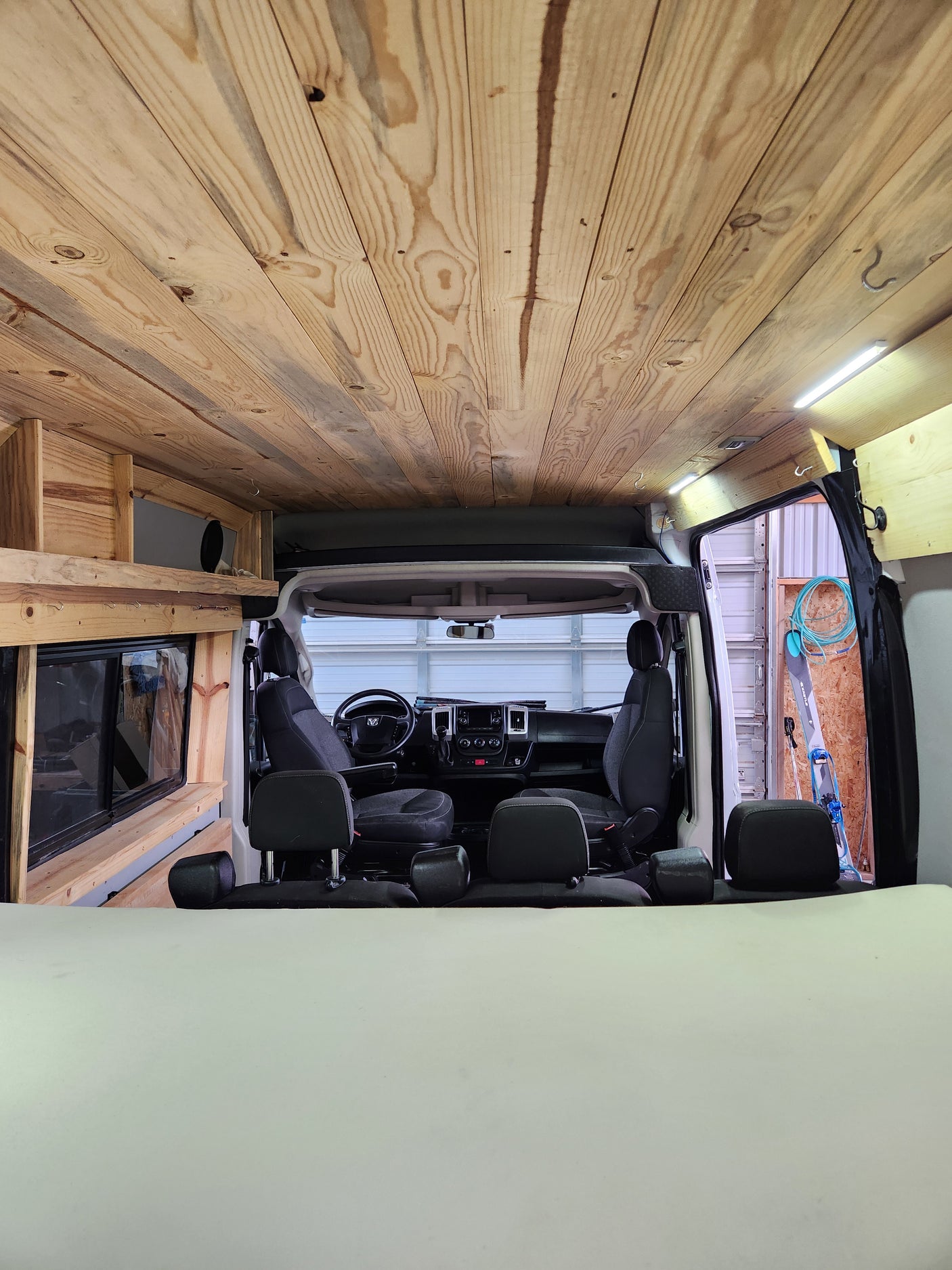 Wood-paneled camper van interior, featuring ceiling, bed, & front cabin. Ideal for RV rental trips.