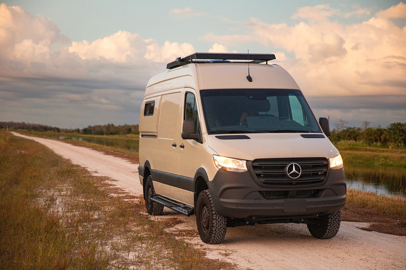 Rugged, tan Mercedes Sprinter camper van RV rental on a dirt road, ideal for nature adventures. — photo 1