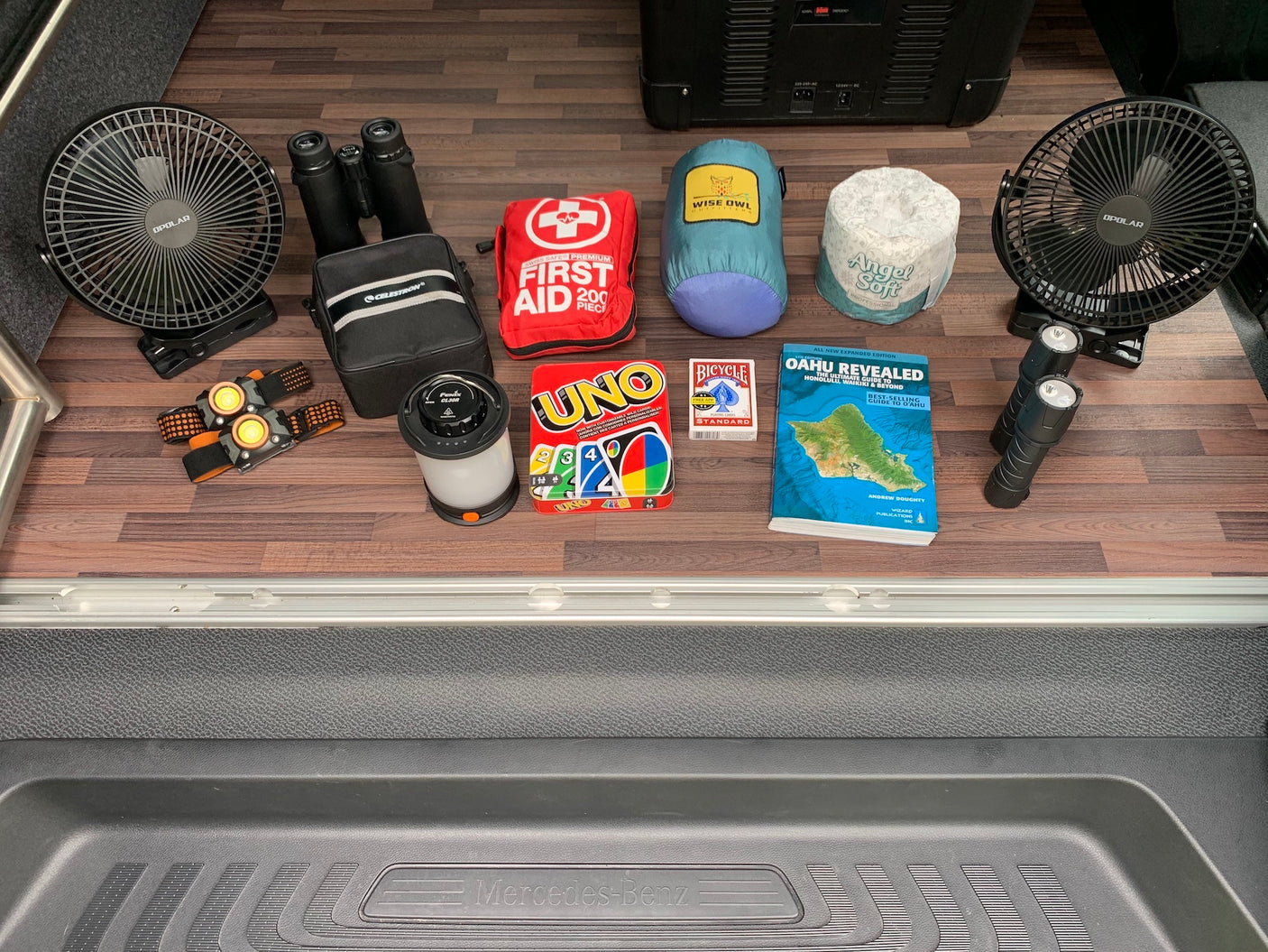 RV rental ready with essential camping gear: fans, lights, first aid, binoculars, games, and an Oahu travel guide.