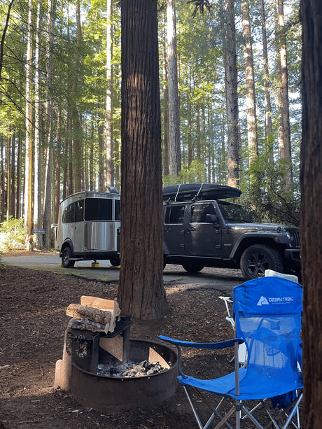  with snowy peaks in the background.|A silver Airstream rv rental on a rugged dirt road