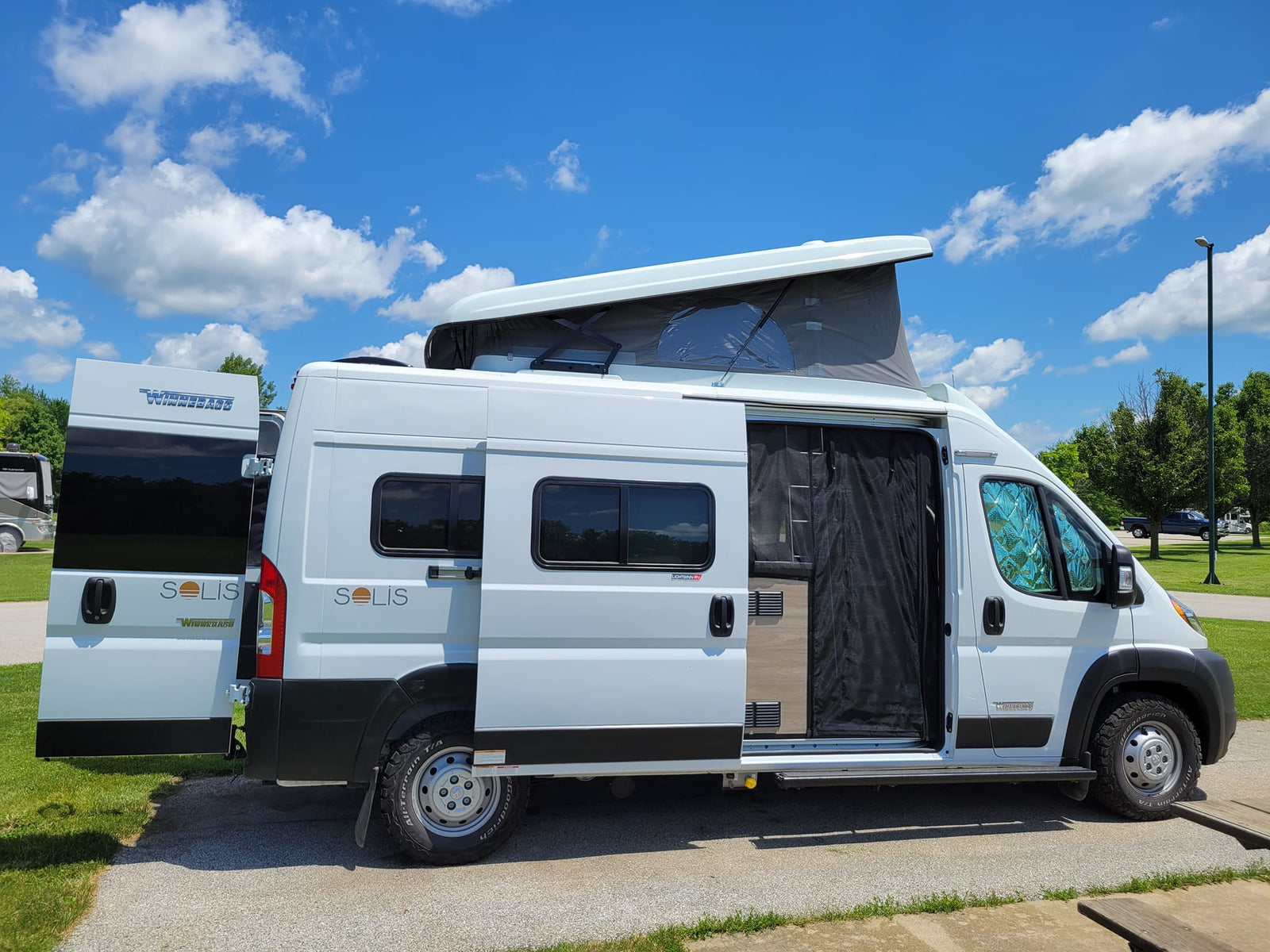 Bright white Winnebago Solis pop-top camper van with doors open, ready for your next RV rental adventure.