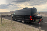 A black luxury rv rental van at White River Valley Overlook, with a rugged landscape under a cloudy sky.