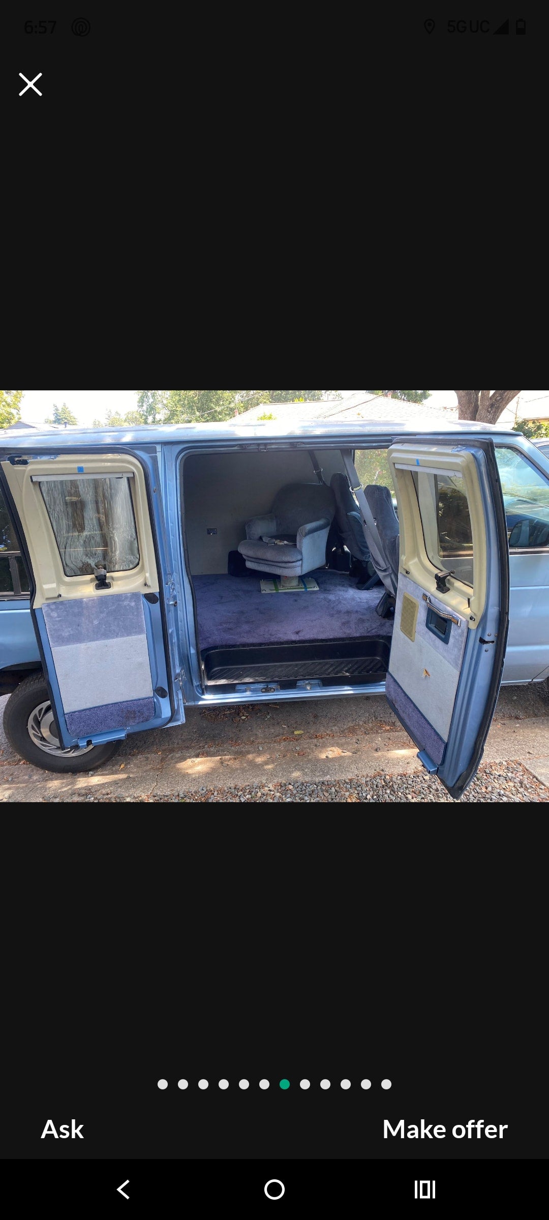 Light blue conversion van's spacious interior for RV rental. Features plush blue carpet & swivel armchair with side doors open.