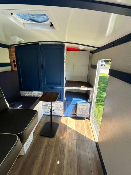 Custom camper interior for your RV rental, with blue cabinets, seating, adjustable table, and a roof fan for cozy travels.