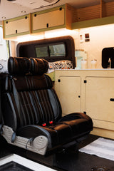 Inside a stylish RV rental: black leather seating, light wood cabinets, and a convenient kitchenette with a coffee maker.