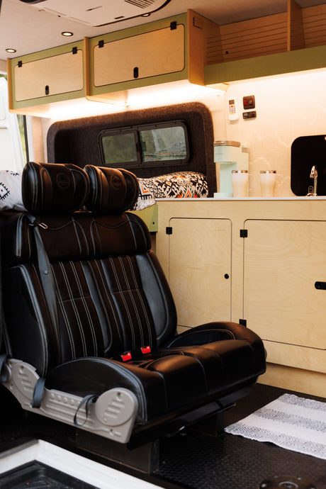 Inside a stylish RV rental: black leather seating, light wood cabinets, and a convenient kitchenette with a coffee maker.