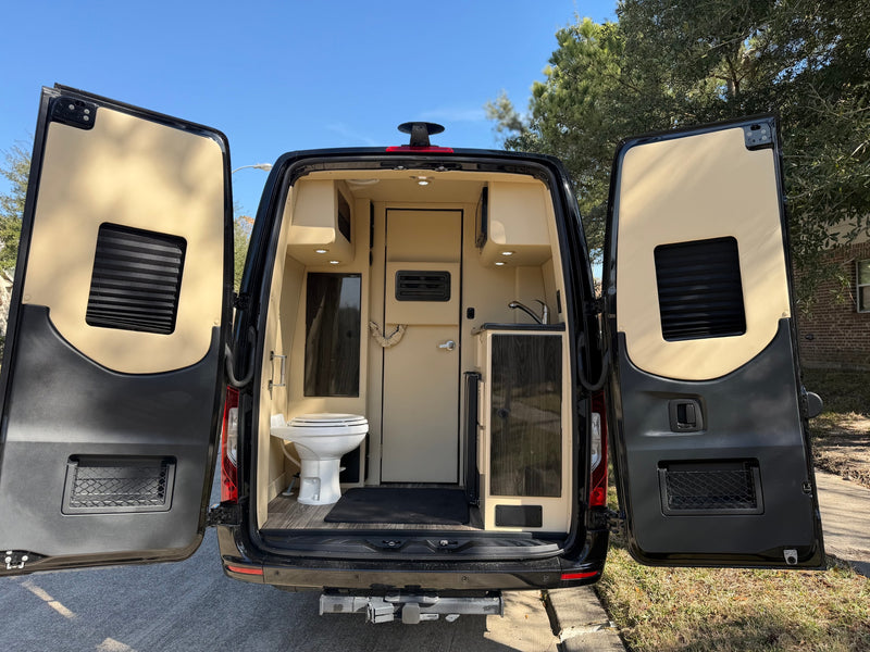 Rear view of an rv rental camper van, doors open, revealing a compact interior with a toilet, sink, and cabinets. — photo 14
