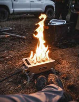 Enjoying a cozy RV rental camping trip. Flames dance in a portable fire pit, warming the feet of a person sitting on the ground.