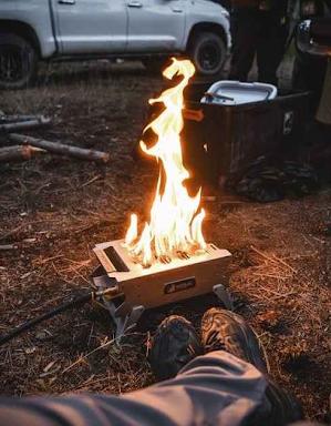 Enjoying a cozy RV rental camping trip. Flames dance in a portable fire pit, warming the feet of a person sitting on the ground.
