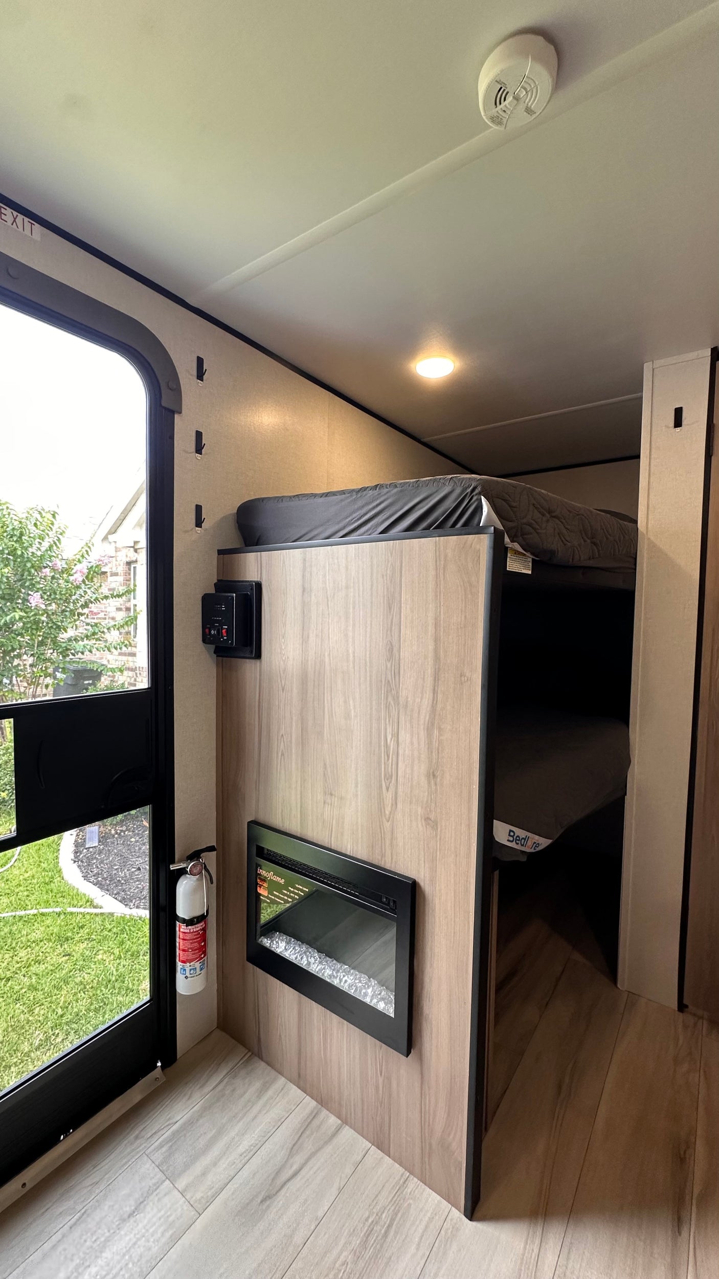 RV rental interior features bunk beds, a wall-mounted electric fireplace, and controls. Safety includes an extinguisher by the exit.