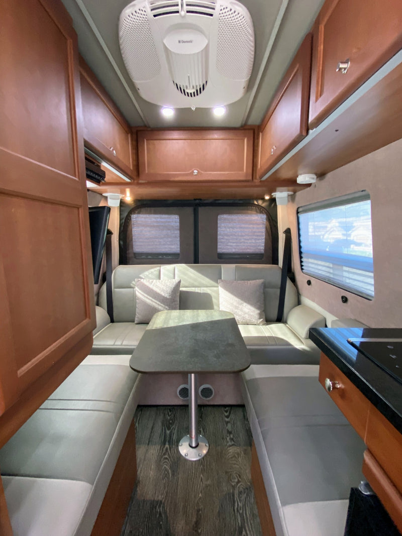  fridge; convertible bed; and wood cabinetry maximize compact living.|Sp|RV rental interior view: driver's cabin with front seats — photo 5