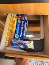 RV rental kitchen drawer storing aluminum foil, plastic wrap, lemon trash bags, and cutting boards.