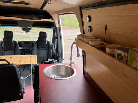 RV rental: Interior of a custom camper van featuring a kitchen sink, modular table, and smart storage.