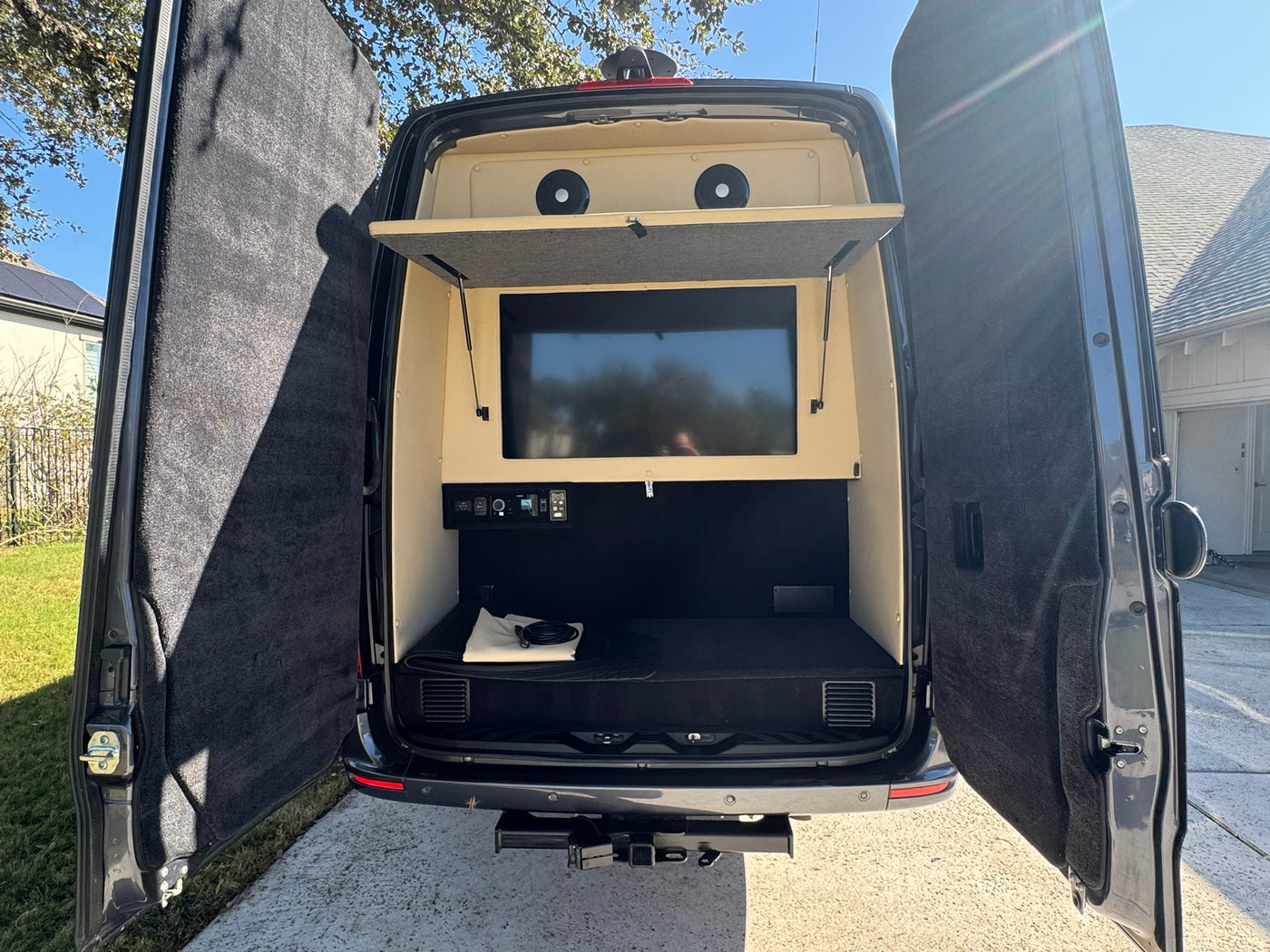 is parked on a sunny driveway beside a house and trees.|Custom gray Mercedes Sprinter van — photo 3