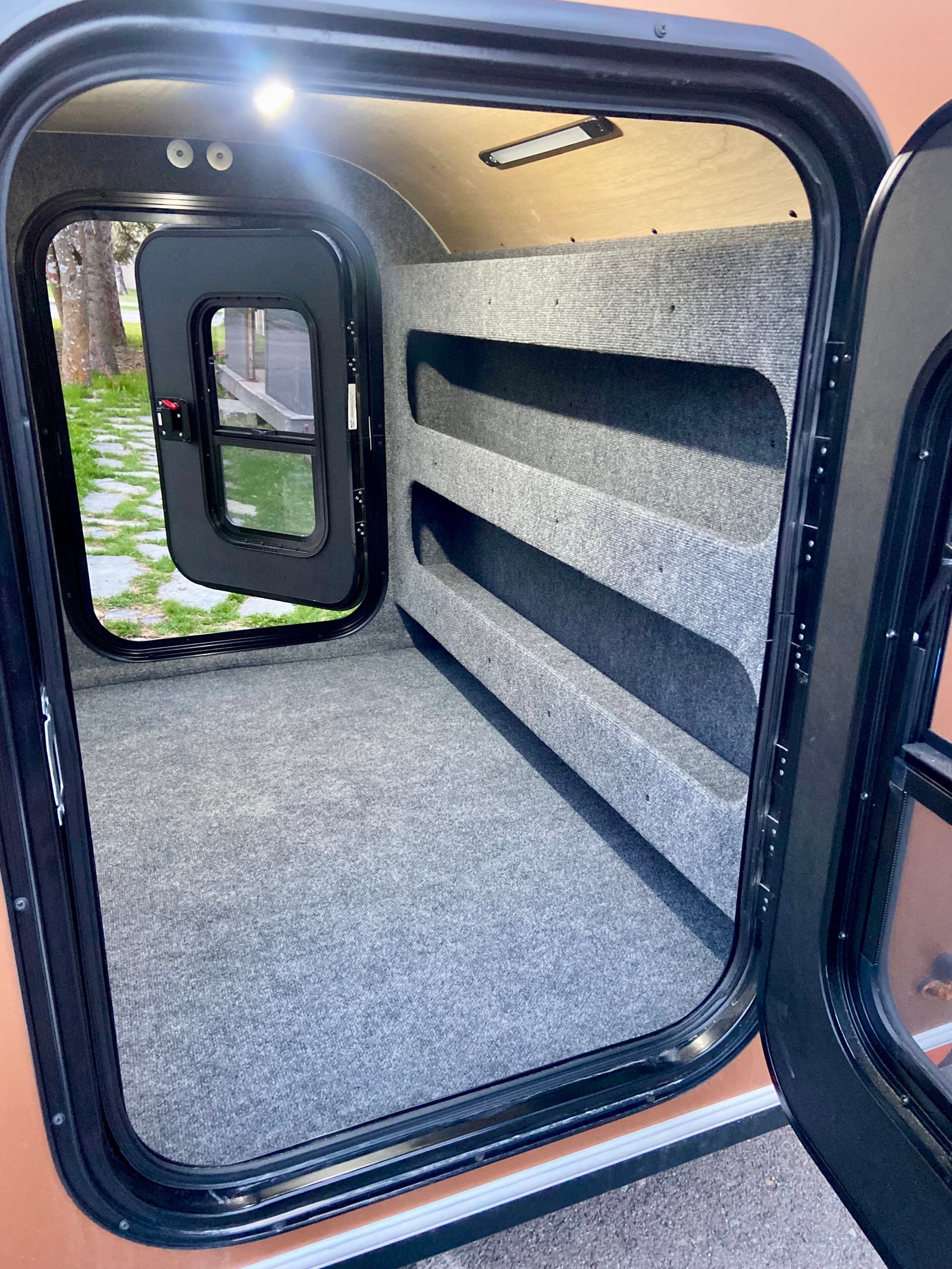 Explore this RV rental's cozy, carpeted interior, featuring integrated shelving for storage and ample space for sleeping.