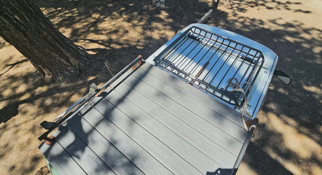 Overhead of an RV rental: custom roof deck, front cargo rack. Parked under dappled tree shade. Ideal for outdoor adventures.