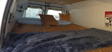 Cozy RV rental camper van interior: a comfortable bed with pillows & blankets, and a winter view outside. Perfect for van life.