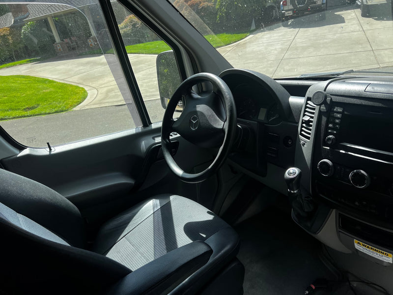  parked outdoors. Features an Oregon plate & "That Triathlon Life" sticker.|RV rental with roof-mounted camera and white body reflecting a blue sky with trees.|This RV rental's roof features solar panels and a vent — photo 8