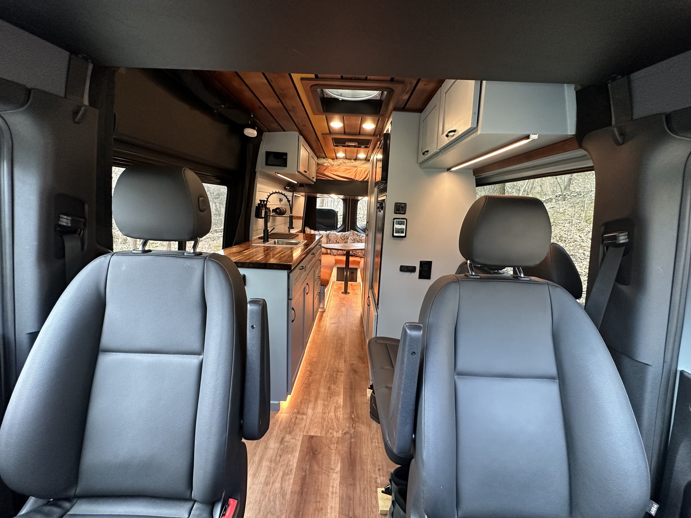 RV rental camper van interior: modern kitchen, dining, and sleeping areas with wood accents and ambient lighting.