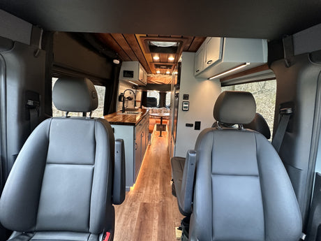 RV rental camper van interior: modern kitchen, dining, and sleeping areas with wood accents and ambient lighting.