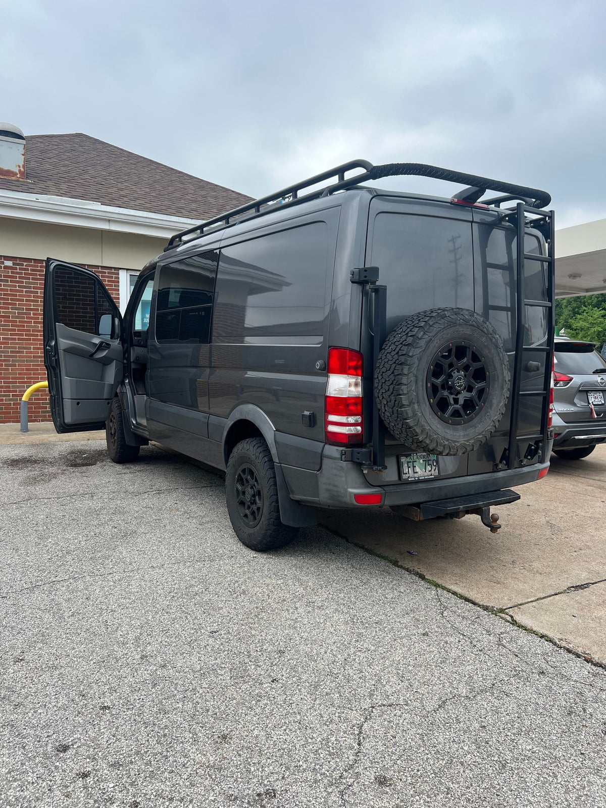 Grey Sprinter RV rental, equipped for adventure with roof rack, ladder, and rear spare tire, parked on asphalt. — photo 4