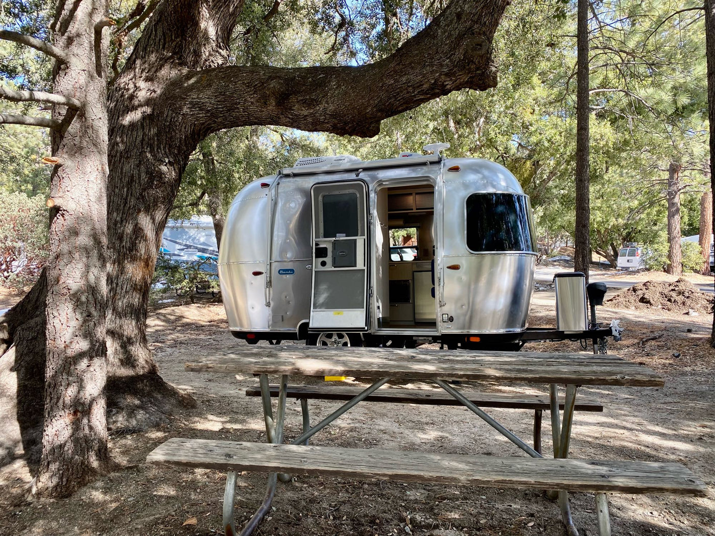  with an open door and picnic table in front.|Enjoying the perfect RV rental getaway! This Airstream travel trailer with awning & cozy chairs invites relaxation.|Experience the comfort of this Airstream RV rental interior — photo 2
