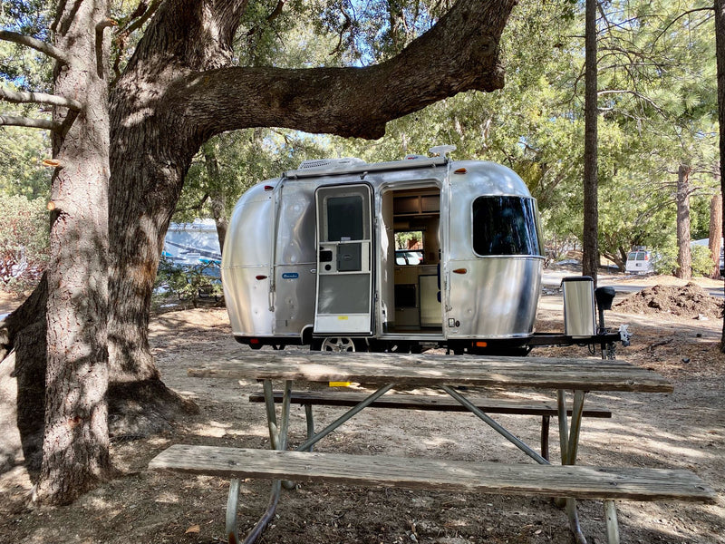  with an open door and picnic table in front.|Enjoying the perfect RV rental getaway! This Airstream travel trailer with awning & cozy chairs invites relaxation.|Experience the comfort of this Airstream RV rental interior — photo 2