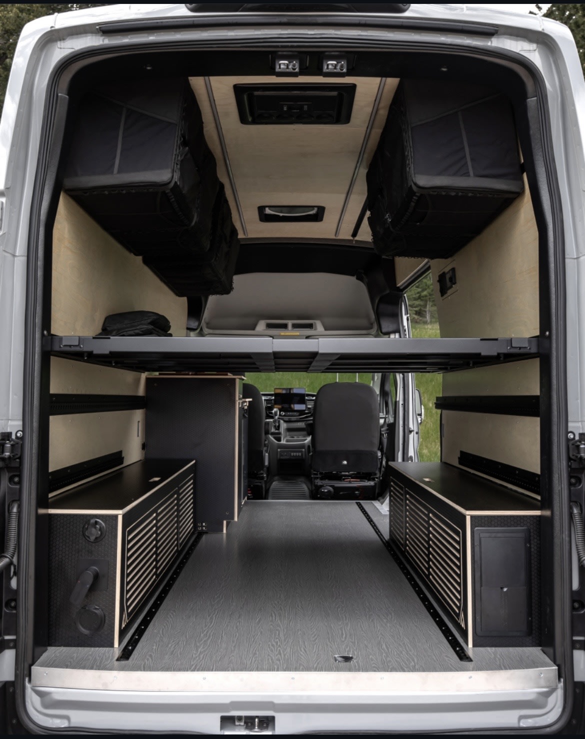 Spacious RV rental interior: customized camper van with modular bed, overhead storage, and built-in cabinets.