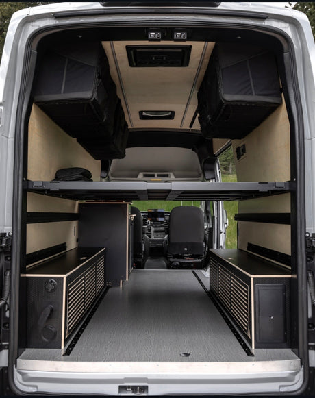Spacious RV rental interior: customized camper van with modular bed, overhead storage, and built-in cabinets.