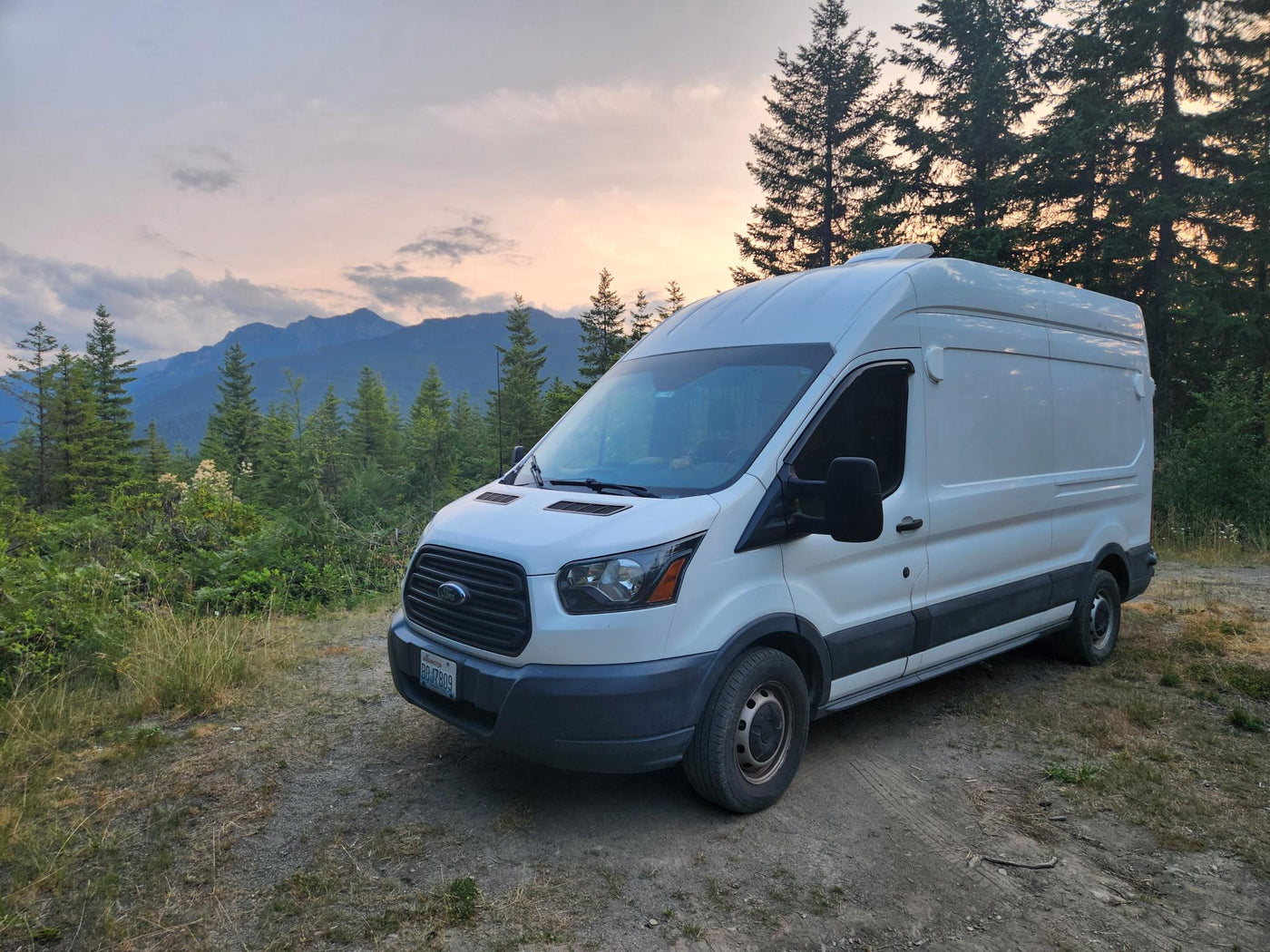 This white RV rental van is parked on a dirt road — photo 1