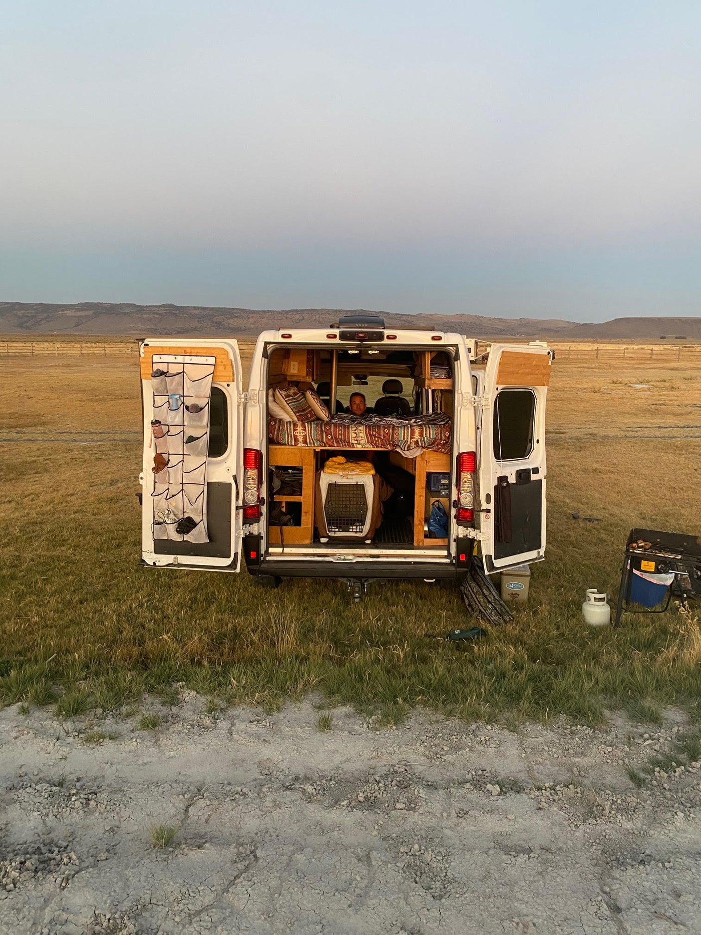  and a person relaxing while watching a projected screen.|Cozy camper van interior featuring a lit wood stove — photo 7
