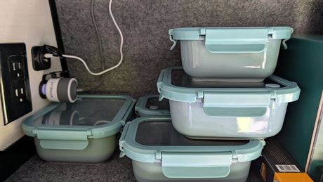 Inside an RV rental, showing neat stackable food storage containers and a convenient device charging station.